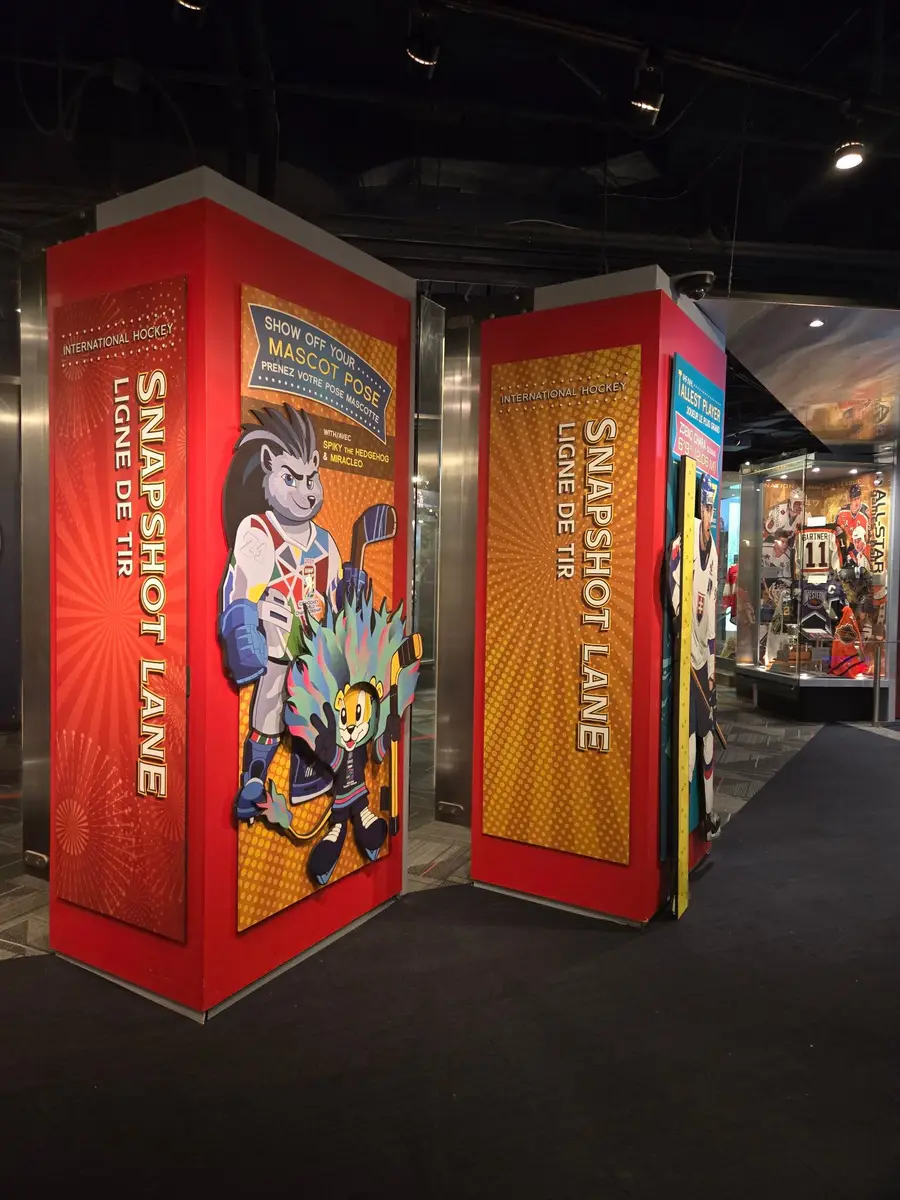 Completed snapshot lane entrance columns display mascot graphics for an international hockey interactive exhibit.