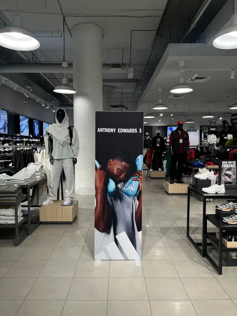 A tall Anthony Edwards 3 freestanding banner display standing on the sales floor of a Foot Locker store.