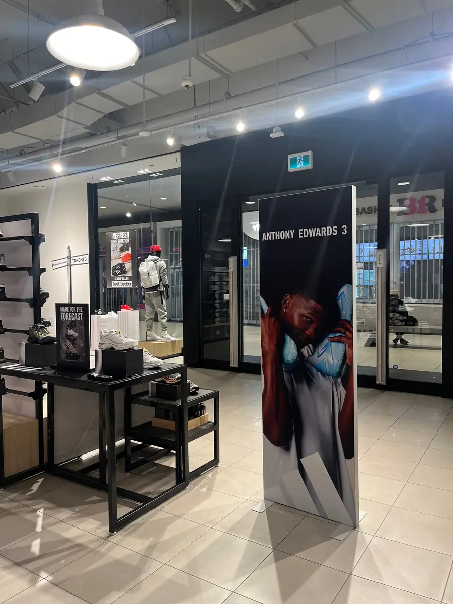 An Anthony Edwards 3 branded freestanding display banner positioned at the entrance of a Foot Locker Toronto retail store.