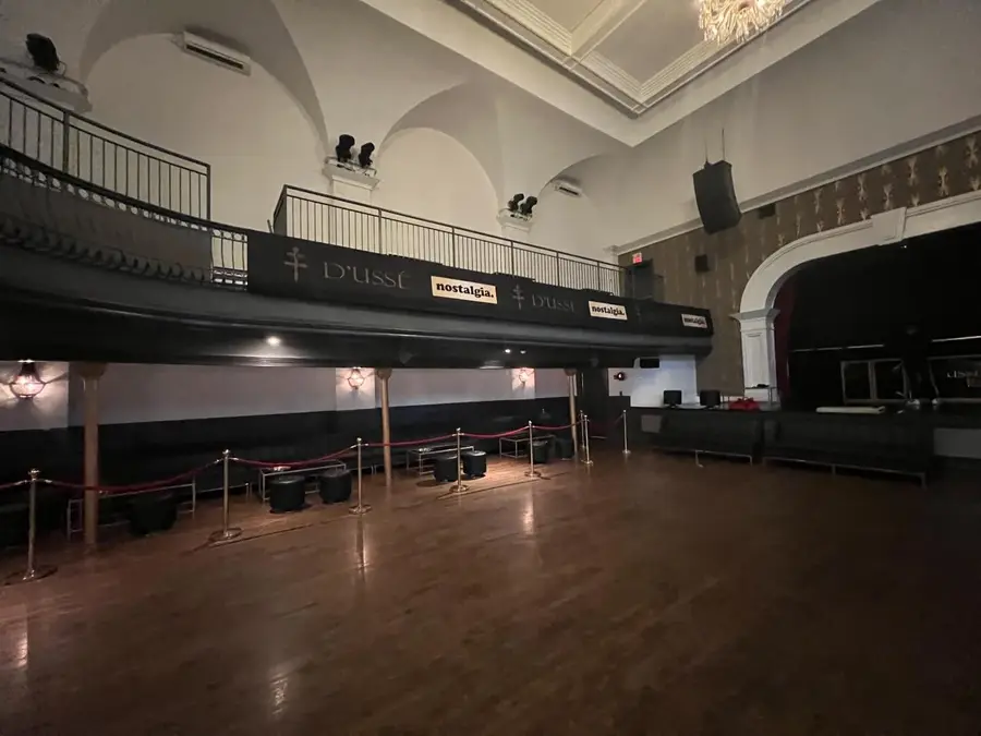 A side view of a historic venue interior shows VIP lounge seating, rope barriers, a mezzanine level, and D'USSÉ and Nostalgia branded signage.