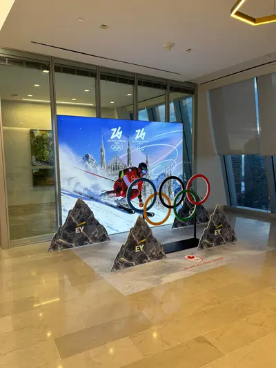 A full Milano Cortina 2026 Team Canada LED display with an Olympic rings prop and multiple mountain cutouts installed in an upscale corporate lobby.