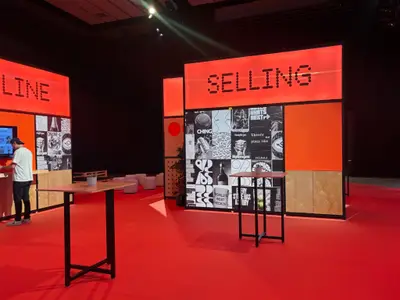 Shopify Selling and Online product booths display bold red illuminated signage and collage-style graphic walls in an event hall.